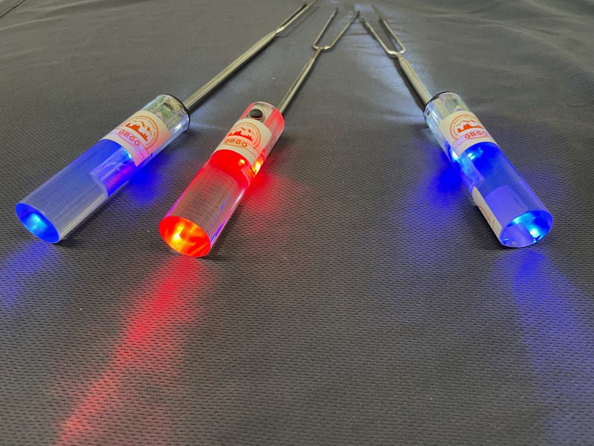 Three LED skewers with red, blue, and green lights on a gray surface. Invented by GBGO the Light Pal is your bff!